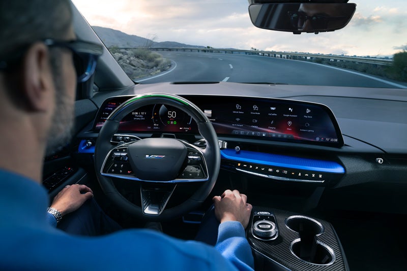 Front View of the 2026 OPTIQ-V Driving Through the Dusk Utilizing its Headlights | Fitzgerald Cadillac Frederick in Frederick MD