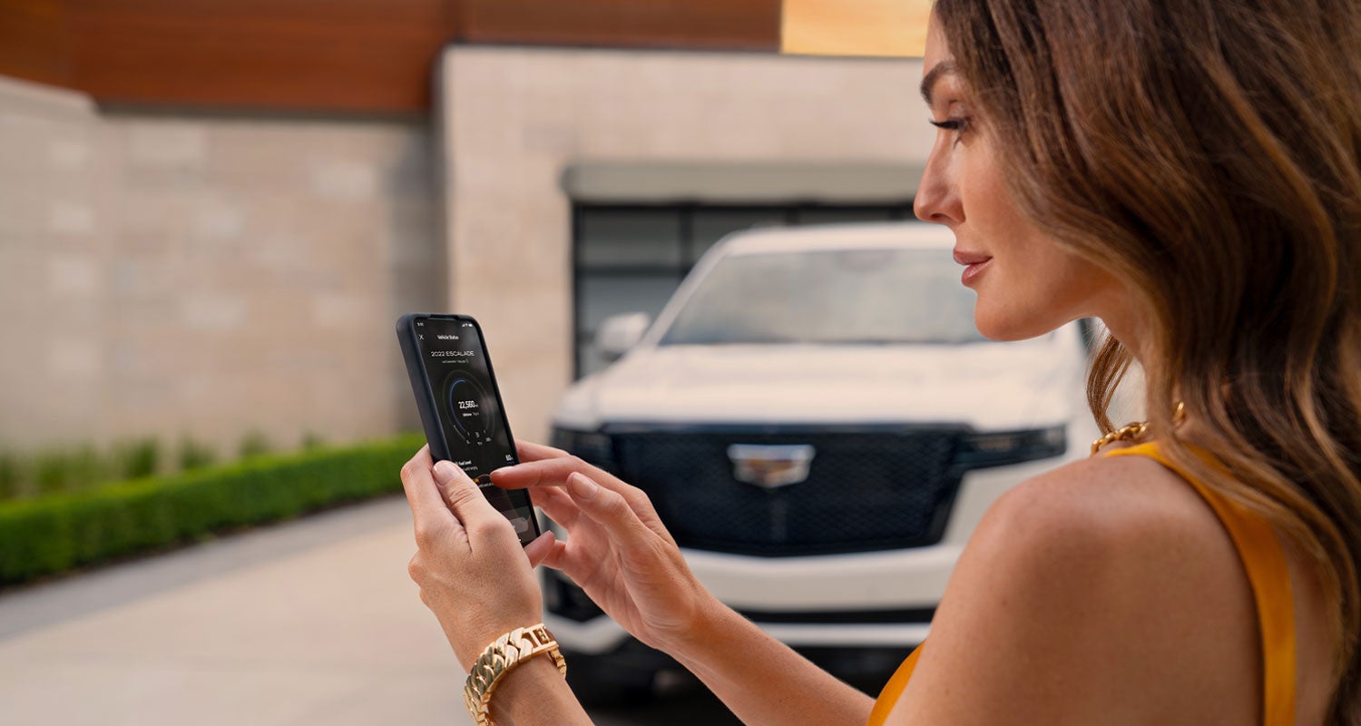 lady checking her mobile with a Cadillac vehicle background | Fitzgerald Cadillac Frederick in Frederick MD
